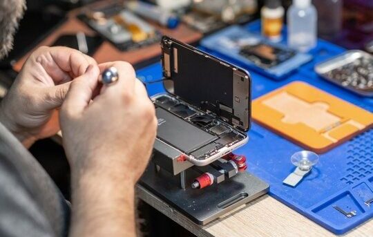 Tekniker reparerar en isärmonterad smartphone med precisionsverktyg