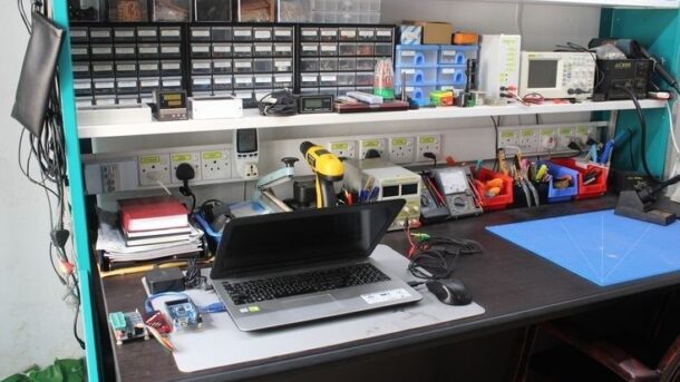 Elektronikverkstad med laptop, mätinstrument och sorterade reservdelar